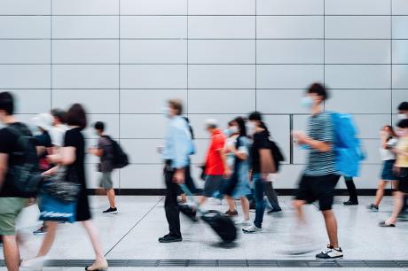 Blurred motion of a crowd of busy commuters with protective face mask walking through platforms at subway station